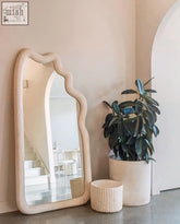 Cream-colored tochio mirror with a fluid frame featuring wavy edges and a smooth matte finish for home decor