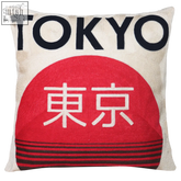 A cream-colored tokyo needlepoint cushion with bold black lettering red half-circle and white japanese characters