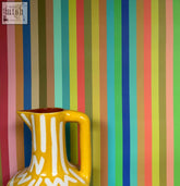 Bright yellow ceramic pitcher with white tonal stripe wallpaper style vertical stripes and reddish brown interior