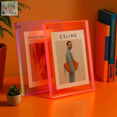 Vibrant transparent acrylic picture frames in pink and orange with silver corner fasteners holding printed images