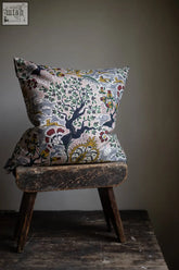A square tree of life eden cushion in vintage french textile design with intricate bird floral motif in muted tones made from ethically sourced materials