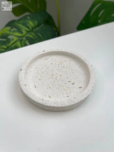 A round off-white terrazzo trinket dish with speckled texture and subtle mother of pearl fragments