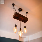 Rustic wooden beam triple pendant light with oak finish and heart bulbs hanging from black chains with hanging kit