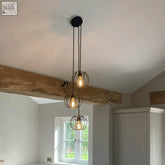Industrial-style triple pendant hanging lights with black ceiling cap and pumpkin cage shades for kitchen island lighting