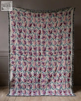 A soft cream-colored woven tulip kisses blanket with purple and pink tulips and fringed edges