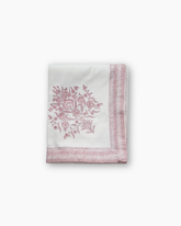 A delicate white handkerchief with pink floral embroidery and fringed border complements varmala hand block print pink tablecloth