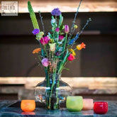 Clear glass vase from dutz collection made of recycled blown glass holding colorful assorted flowers