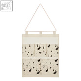 Off-white fabric white wall hanging pocket organiser with black inkblot pattern and triangular wire hanger
