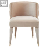 A blush pink velvet tufted curved dining chair with gold-toned legs perfect for stylish beige velvet seating