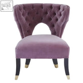 A plush lilac velvet accent chair with tufted curved back and elegant black legs with gold accents