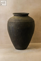 A vintage black asian ceramic jar with a matte finish rounded body and narrow neck perfect for decor