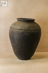 Dark weathered vintage black asian ceramic jar with rope-like decorative band around its midsection vintage black asian pots