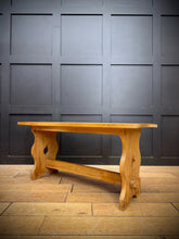 Light oak wooden trestle end bench with curved carved legs and central stretcher for dining or coffee table use