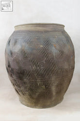 Vintage dark pot storage jar with unglazed exterior and textured diagonal ridges in dark gray ceramic