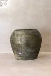 A vintage dark pot made of weathered dark gray ceramic with a rounded body and slightly flared rim