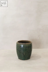 Vintage emerald green pot made of glossy ceramic with subtle engraved branch patterns in a small cylindrical shape