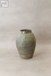 A matte green ceramic yunnan pot yp16 with textured handcrafted surface and a metallic rim as a preservation vessel