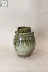A vintage glazed green ceramic jar with concentric circles and loop handles perfect as a preservation vessel