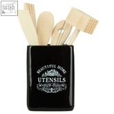 Vintage home black ceramic utensil holder with white engraved text holding six wooden kitchen tools