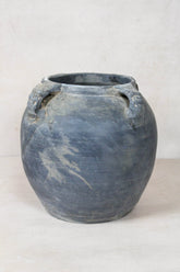 A vintage lion ears dark pot made of weathered dark gray ceramic with carved animal-headed handles