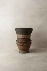 Vintage nupe pot stand 4.2 with weathered terracotta body and intricate carved bands around its midsection