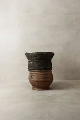 Vintage nupe pot stand 4.3 with a weathered two-toned ceramic pot featuring dark upper section and lighter brown base