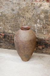 A rustic brown ceramic vintage old asian pot with a textured handcrafted surface and slightly flared rim