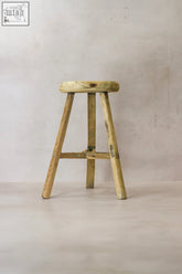 Vintage rustic elm wood stool with round worn seat and three sturdy legs joined by crossbar wood stool