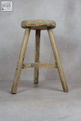 Vintage rustic elm wood stool with a round weathered seat and three sturdy legs connected by a support beam