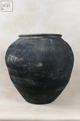 A vintage textured grey ceramic jar with a rounded body and aged patina ribbed design perfect for decor