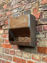 Rustic vintage wall mounted metal planter with weathered reddish brown patina and three small rods inside