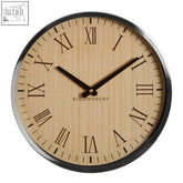 A sleek vitus natural and silver wall clock with a light wood grain face black roman numerals and a silver wall frame