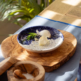 Wave ceramic garlic grater with deep blue speckled ceramic garlic bowl and white exterior on olive wood board