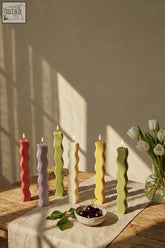A set of six colorful wavy pillar candles in red lavender green cream yellow and olive perfect for decor