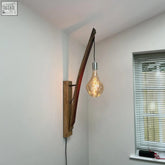 Whiskey stave wall light with curved reclaimed oak arm and clear glass shade showing exposed filament bulb price depending on client page