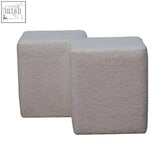 Two light gray textured concrete cubes arranged in an l-shape white boucle twin footstool for versatile seating