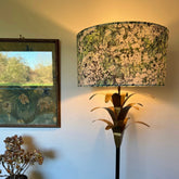 A tall brass floor lamp with a white flowers velvet drum lampshade featuring green floral pattern and fitting sits 3-4cm ceiling shade