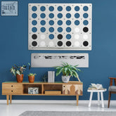 White metal wall art with a grid of blue white and black cutouts for the giant mega connect four wall game