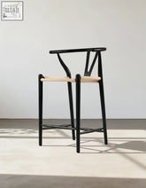 Black wishbone bar stool with ash wood frame and light woven rope seat and backrest for stylish seating