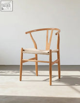Light-colored wishbone dining chair with y-shaped wooden back and woven rattan seat ideal for coffee table set offers