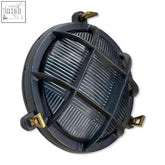 Dark gray cast iron wall light with brass hardware and ribbed glass panel in a nautical bulkhead wall light design