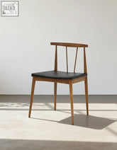 Wyatt dining chair with a minimalist wooden frame and sleek black leather seat perfect for dining areas