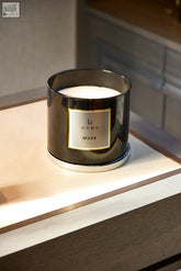 A sleek dark metallic cylindrical xl candle holder with white wax and a gold label reading li home musk white musk