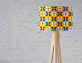 Yellow lampshade with a retro blue and white design on a wooden tripod table lamp base
