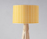 Yellow table lamp with white geometric stripes and a wooden tripod base perfect as a lamp shade