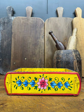 Vibrant yellow wooden painted brick mould with hand-painted pink and blue floral motifs used as herb planter or storage box tray