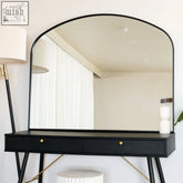 Black metal gentle arch mirror with sleek frame mounted above matching black vanity with gold drawer pulls and angled legs