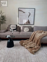 A tan faux fur throw draped over a gray sectional sofa perfect for cozying up with the yūgen throw