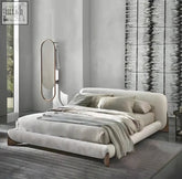 Modern yukina bed with a sculptural frame wrapped in soft off-white fabric and wooden legs for stylish comfort