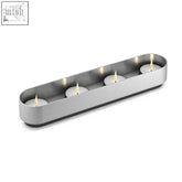 Modern brushed stainless steel lonta tealight holder with four lit tea light candles for stylish decor